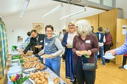 Das Bild zeigt den Frühstücksempfang des Tourismustages 2025. Lächelnde Menschen stehen vor dem Buffet mit Tellern in der Hand.