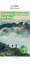 Das Bild zeigt das Titelbild der Broschüre "Sicher am Berg". Darauf zu sehen sind Wanderer in alpinem Gelände, dahinter wolkenverhangene Berggipfel.