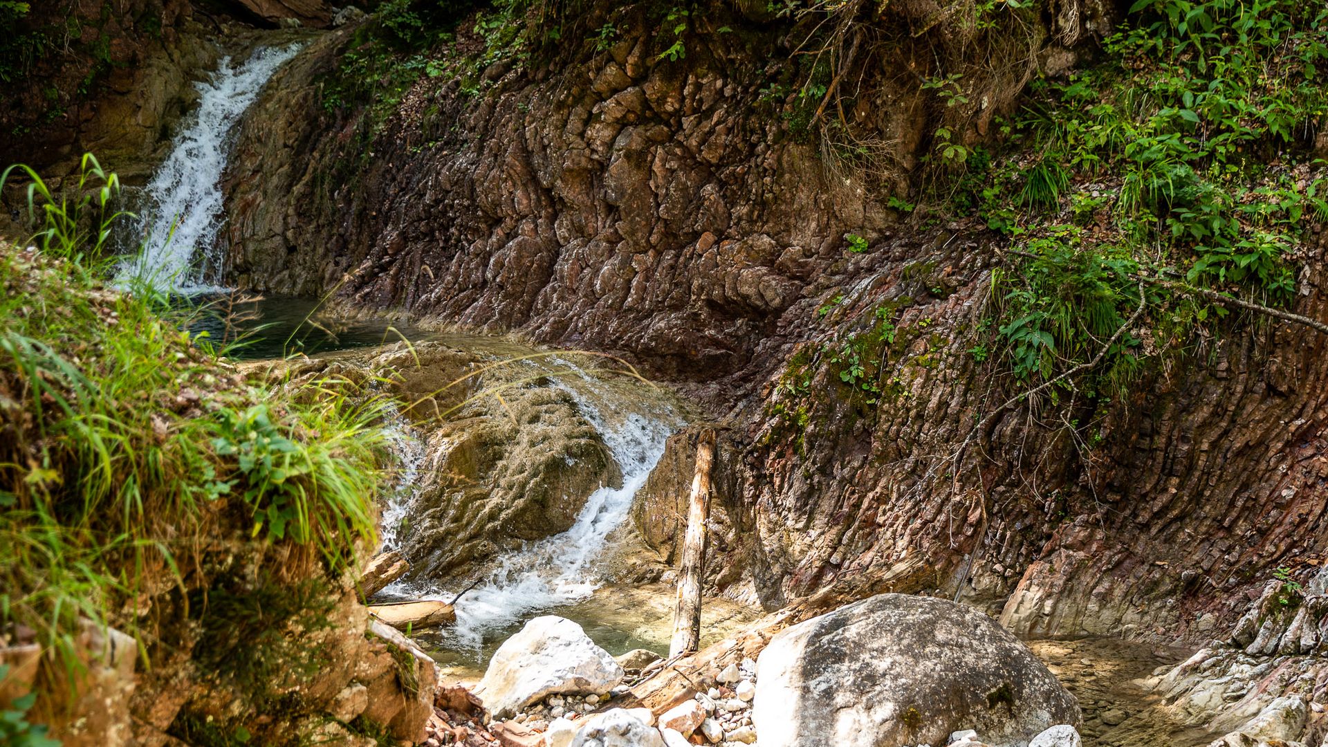 Das Wasser der Schleifmühlenklamm schlängelt sich über braune Felsen.